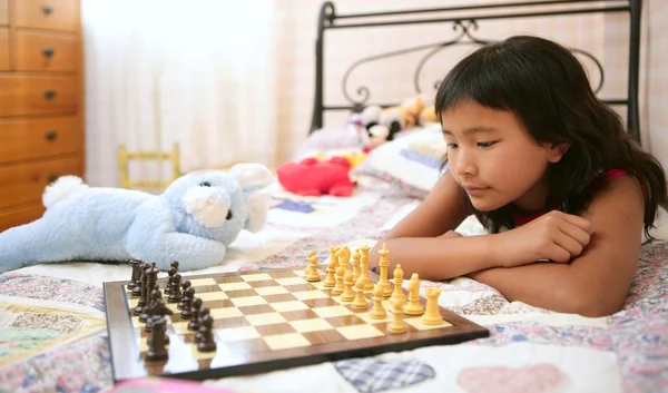 Азиатская девочка играет в шахматы с плюшевым кроликом — стоковое фото