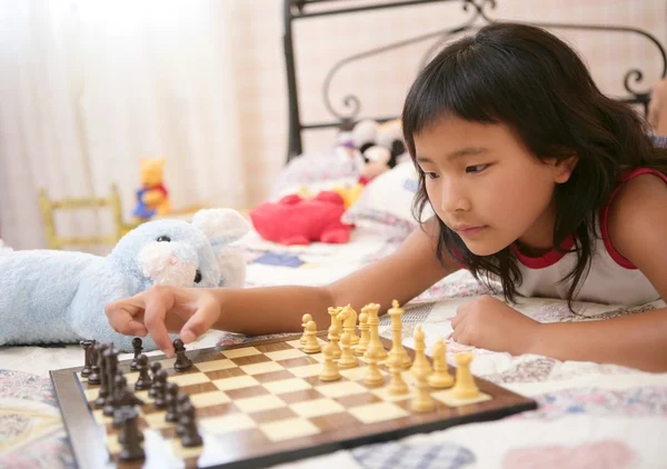 Asiatisches kleines Mädchen spielt Schach mit Teddykaninchen — Stockfoto