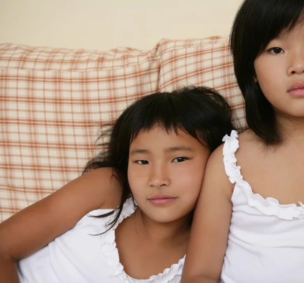 Asiatiska systrar poserar stående på soffan — Stockfoto