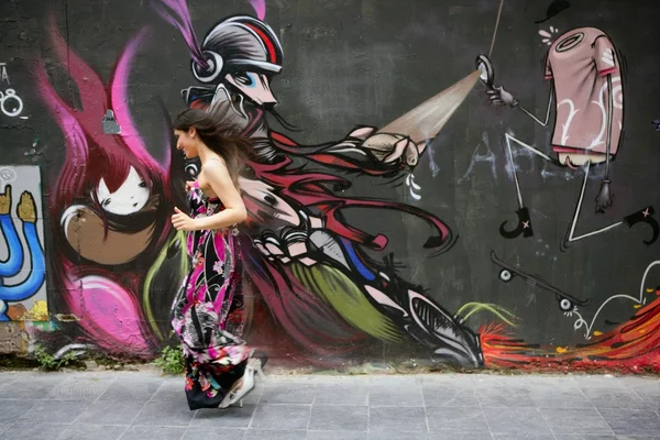 Elegant fashion woman running over urban graffiti — Stock Photo, Image