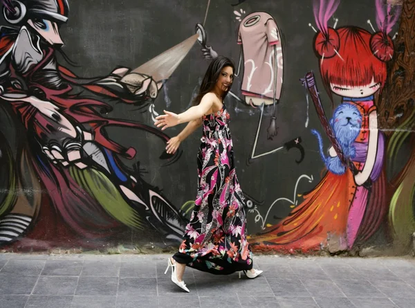 Elegant fashion woman running over urban graffiti — Stock Photo, Image