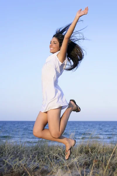Vacker brunett hoppning på stranden — Stockfoto