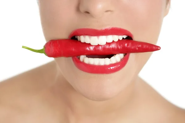 Krásná žena zuby jíst červené papriky — Stock fotografie