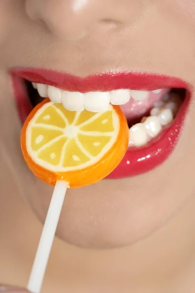 Pirulito colorido em dentes de mulher perfeita — Fotografia de Stock