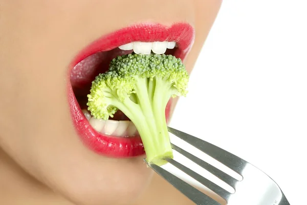 Brócolis em garfo de aço na boca da mulher — Fotografia de Stock