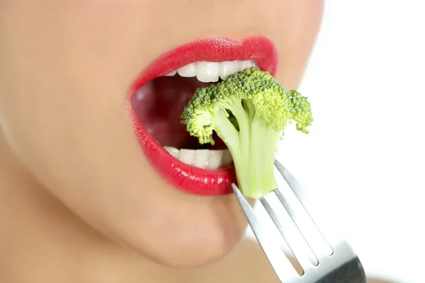 Broccoli on steel fork in woman mouth — Stock Photo, Image