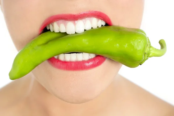Krásná žena zuby jíst zeleného pepře — Stock fotografie