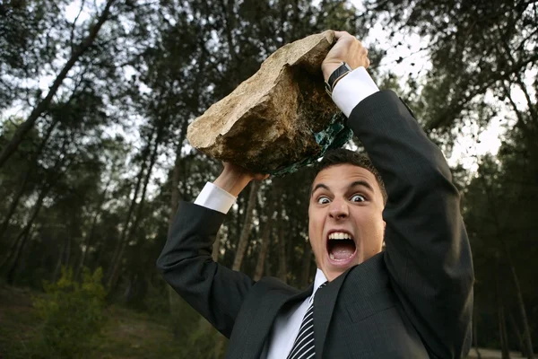 Разгневанный бизнесмен на открытом воздухе, большой камень в руках — стоковое фото
