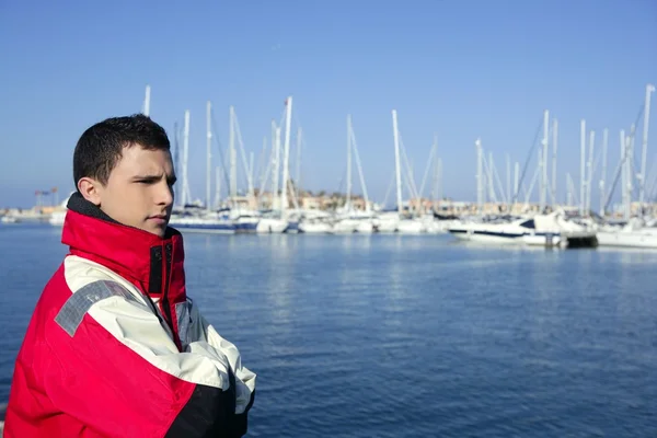 Όμορφο αγόρι στο λιμάνι με κόκκινο παλτό του θαλάσσιου — Φωτογραφία Αρχείου