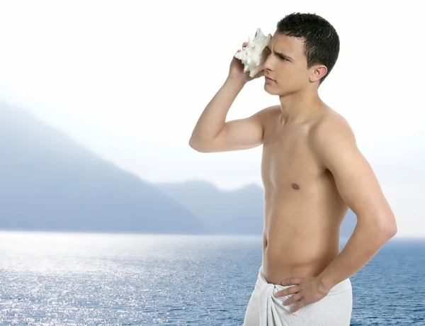 年轻英俊的男人洗完澡听海贝壳 — 图库照片