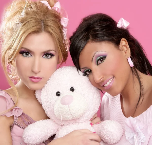 Блондинка и брюнетка обнимают розового плюшевого мишку — стоковое фото