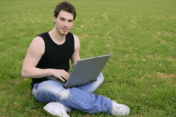 Studerande ung man bärbar dator på äng — Stockfoto