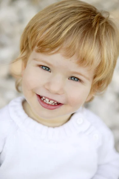 Niño rubio sonriendo sobre un fondo de piedras rodantes —  Fotos de Stock