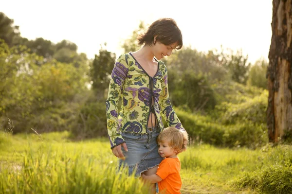 Figlio abbraccio sua madre in verde all'aperto — Foto Stock