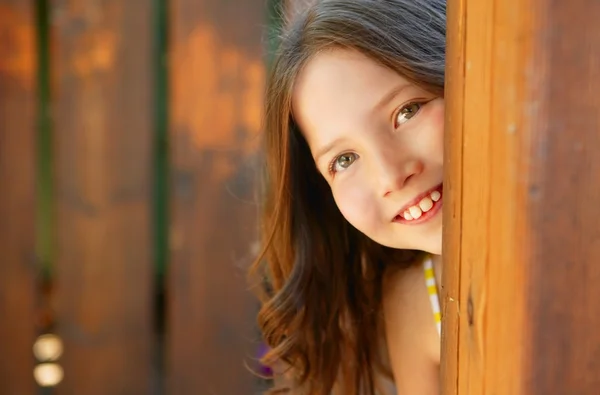 Menina bonita atrás da porta de madeira — Fotografia de Stock