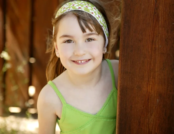 Mooie jonge meisje achter de houten deur — Stockfoto