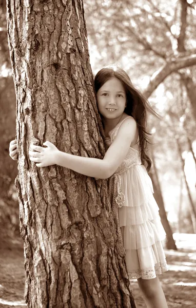Teen girel sarılmak bir ağaç gövdesi, çam ormanı — Stok fotoğraf