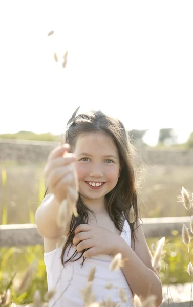 Mädchen im Park spielt mit Blütenspitze — Stockfoto