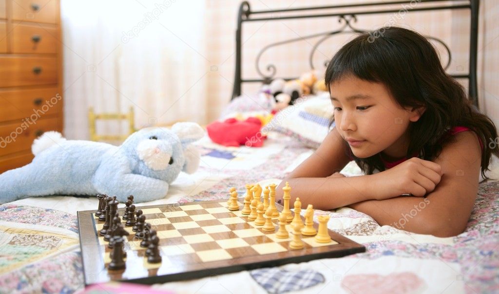 Asian little girl playing chess with teddy rabbit