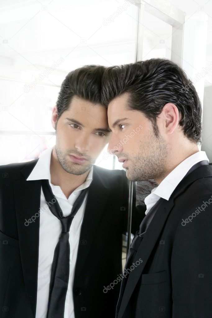 Handsome narcissistic young man looking in a mirror