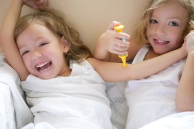 Two little twin sisters, play doctors with syringe clipart