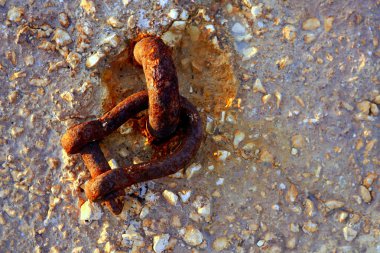 Old rusted shackle on the harbor concrete stones clipart