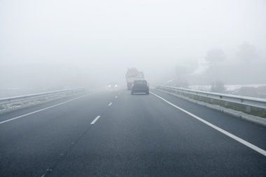 Foggy gray road, cars driving into the fog clipart