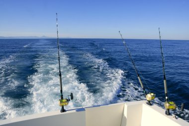 Fishing rod and reel on boat, fishing in blue ocean clipart