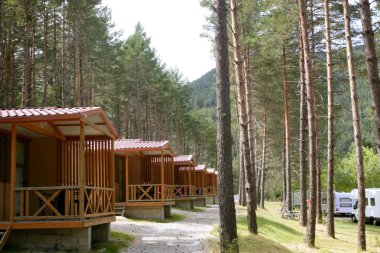 Forest wooden cabins in a mountain camping clipart