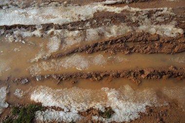 Ice on mud red clay soil road with tyres lines clipart