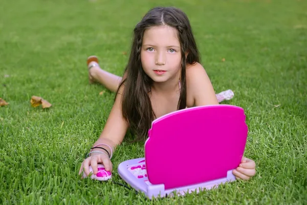 Beautiful little girl playing with pink toy computer — Stock Photo, Image