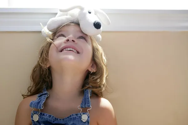 Happy toddler girl with toy dog over head — Stock Photo, Image