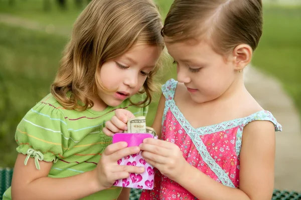 Twee kleine twin meisjes zoeken een dollar notitie in een doos — Stockfoto