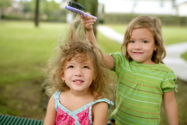 Två tvillingsystrar som låtsas vara frisör — Stockfoto