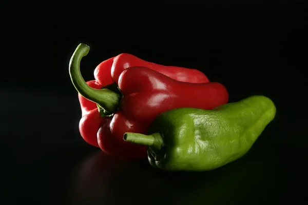 Röd och grön peppar över svart — Stockfoto