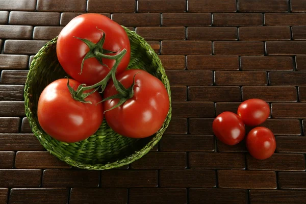 Tomates pequenos e grandes na cesta verde — Fotografia de Stock