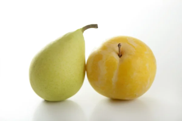 Gul mirabelle och päron på vit bakgrund — Stockfoto
