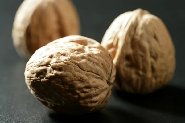 Three walnuts with shells over black background — Stock Photo, Image