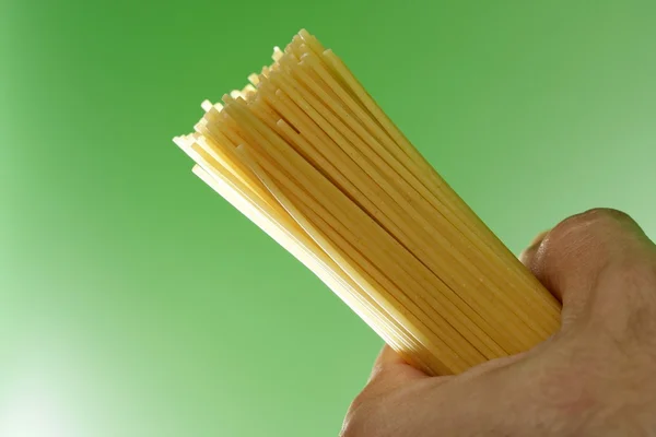 Spaghetti i humand hand på grön bakgrund — Stockfoto