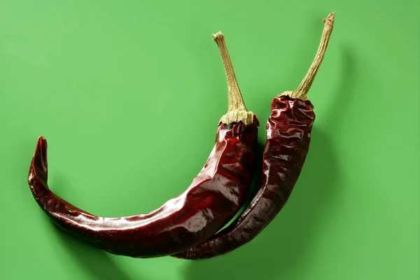 Zwei getrocknete Paprika, Chili, über grünem Hintergrund — Stockfoto