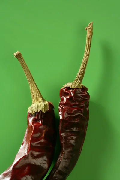 Due peperoni secchi, peperoncino, su fondo verde — Foto Stock
