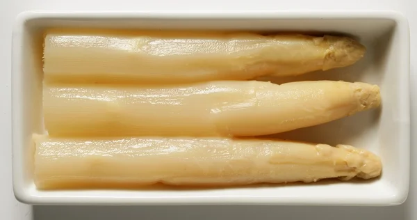 Asparagus in a white dish, three delicious pieces — Zdjęcie stockowe