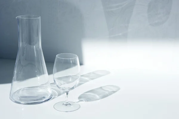Vidro de água e garrafa com sombras transparentes — Fotografia de Stock