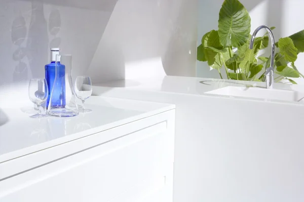 Biały, nowoczesna kuchnia, niebieska butelka wody i roślin — Zdjęcie stockowe