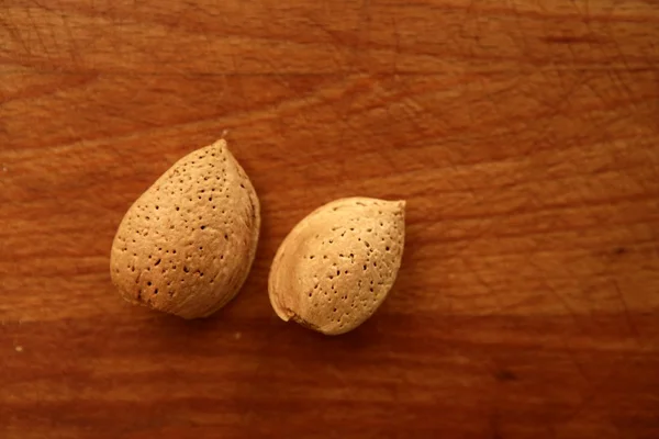 Dwie nakrętki migdałów na złoty stół z drewna — Zdjęcie stockowe