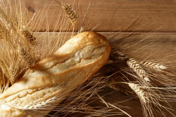 Chleb na drewnianym stole z kolcami pszenicy — Zdjęcie stockowe