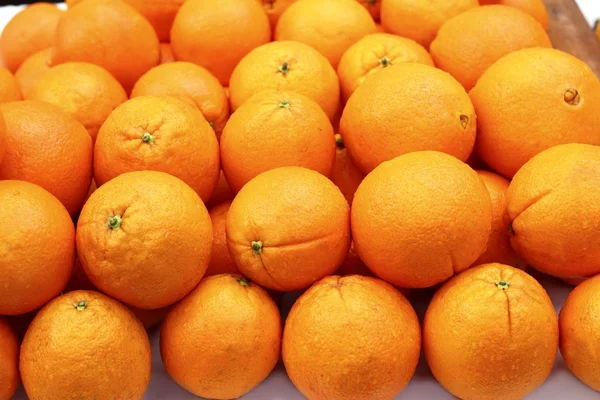 Στοιβάζονται πορτοκαλί φρούτα σειρές που διοργανώνονται στην αγορά — Φωτογραφία Αρχείου