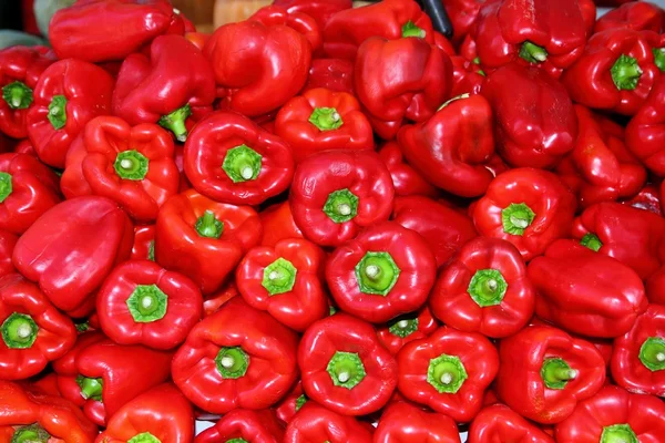 Paprika merah ditumpuk di pasar sebagai latar belakang pola — Stok Foto