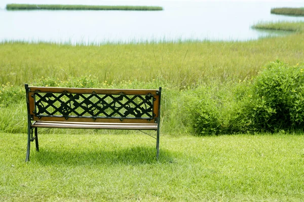 Ławka na zielonej trawie nad jeziorem — Zdjęcie stockowe
