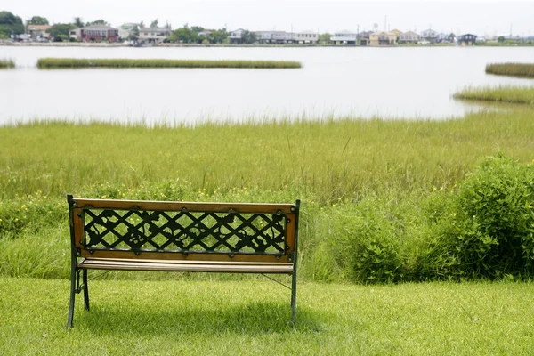 Lavička na zelené trávě na jezeře — Stock fotografie